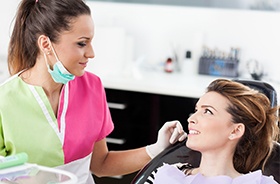 Woman in dental chair smiling at dental team member