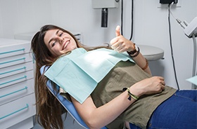 Woman in dental chair giving thumbs up