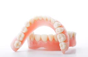 Set of full dentures arranged against neutral background