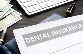 Dental insurance form next to money, pen, and keyboard