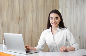 Friendly dental receptionist behind front desk