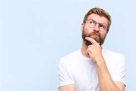 Man in white shirt, thinking about questions about emergency dentistry