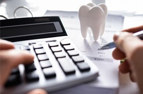 Hands using calculator and holding pen, budgeting for dental care