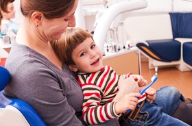 Mother and son sitting in chair in dentist’s office