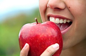 Closeup of patient with dental implants in Branford eating an apple