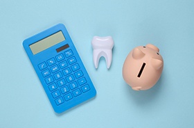Calculator, tooth, and piggy bank against blue background