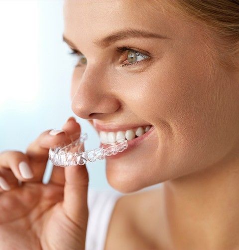 Smiling woman holding Invisalign tray