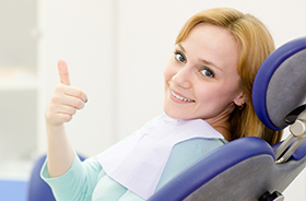 Woman in dental chair giving thumbs up