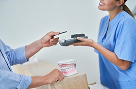 Patient handing over card to pay for dental care