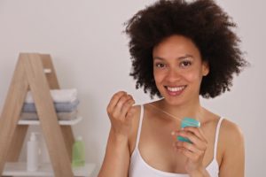 woman using floss to maintain dental hygiene through quarantine