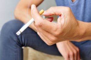 Man with cigarette, wondering about smoking and dental implants