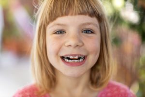 Smiling young girl who has braces with baby teeth in Branford