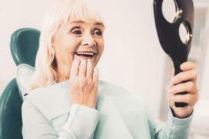 Dental patient holding mirror, admiring her new dentures