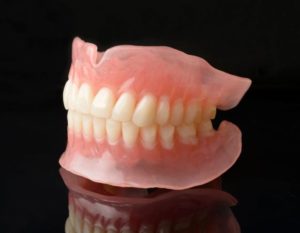 Top and bottom dentures against dark background