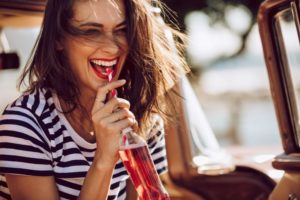 Woman laughing while drinking soda through a straw