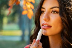 Dark-haired woman applying lip balm