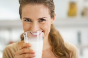 Smiling woman drinking a glass of milk 