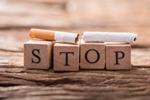 Cigarette on top of four wooden blocks that spell out “stop”